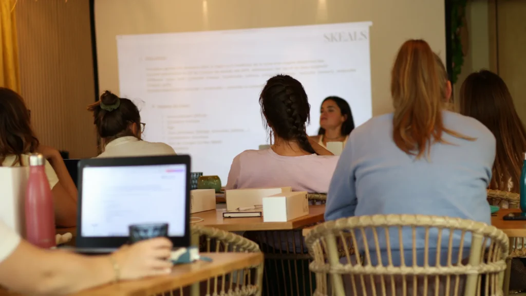 Kinésithérapeutes assis·es en salle de formation face à un support projeté Skeals, ordinateur portable et gourde sur la table